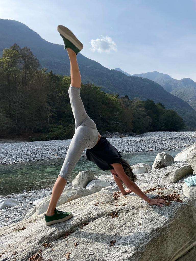 Brigitta Müller Amato in einer Dehnübung auf einem Felsen am Fluss